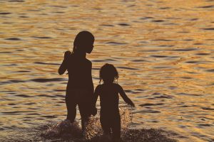 Silhouette of children holding hands in sea
